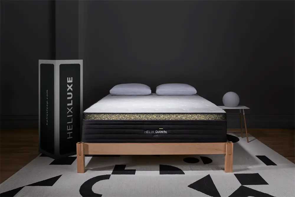 Helix Dawn Luxe 1 Helix Dawn Luxe mattress displayed with two pillows on top, featuring a premium quilted pillow top and a standing box showcasing the Helix Luxe brand.