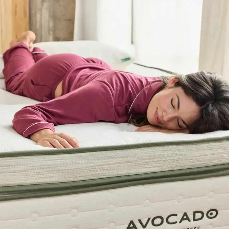 Woman in pajamas sleeping on Avocado Green Mattress Box Top, showcasing comfort and support features.