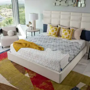 Modern bedroom featuring a King Koil mattress with decorative pillows and a cozy throw blanket, showcasing a stylish bed frame and contemporary decor.