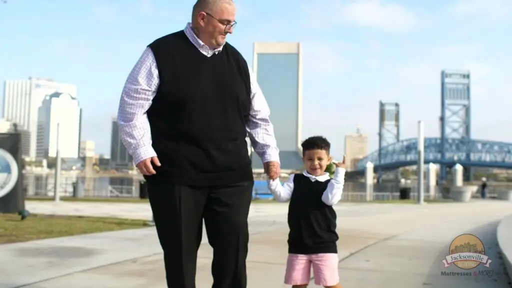 Man and boy walking together in Jacksonville, showcasing family connection and community, with city skyline in the background, representing Jacksonville Bedding's commitment to customer relationships and feedback.