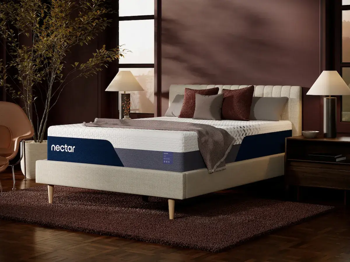 Nectar Luxe Memory Foam 2 Nectar Luxe Memory Foam mattress on a stylish bed frame, featuring plush pillows and a cozy blanket, set in a modern bedroom with decorative plants and lamps.